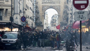 Manifestantes diante de policiais de choque após declaração do ministro do Interior francês, Gerald Darmanin (invisível), no local onde vários tiros foram disparados ao longo da rue d'Enghien