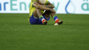 Neymar sentado com o joelho dobrado e a cabeça baixa