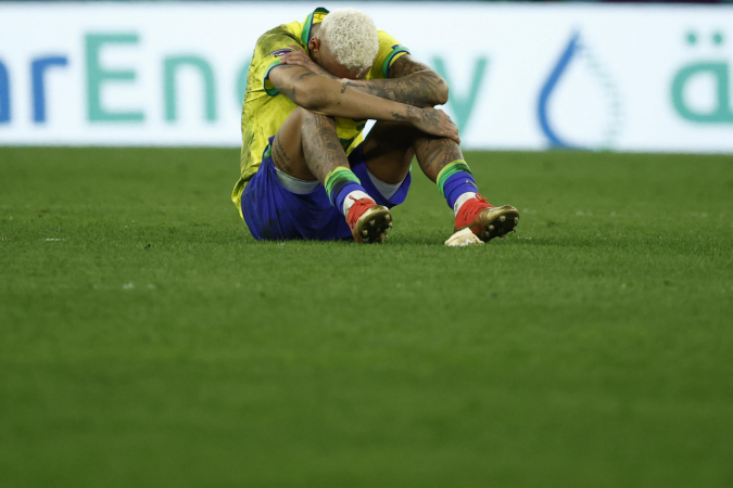Neymar sentado com o joelho dobrado e a cabeça baixa