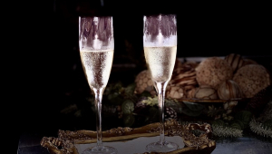 Taças de vinho em cima da mesa, em frente a uma cesta de pães, em ambiente escuri