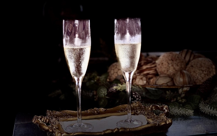 Taças de vinho em cima da mesa, em frente a uma cesta de pães, em ambiente escuri