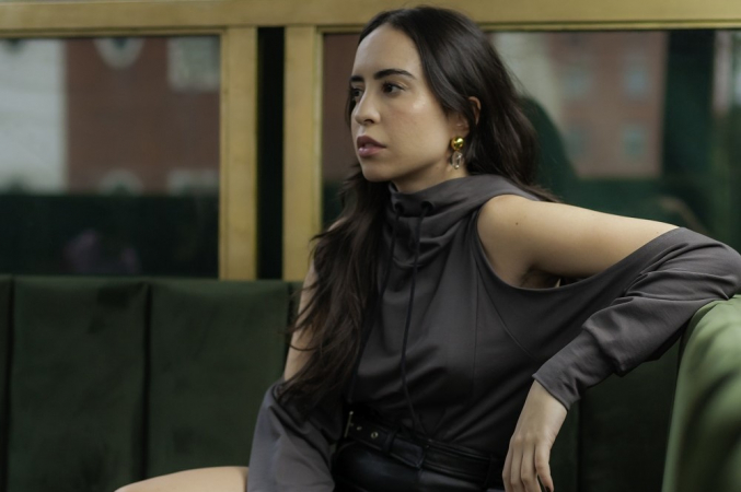 Jovem mulher branca sentada em sofá com as pernas cruzadas