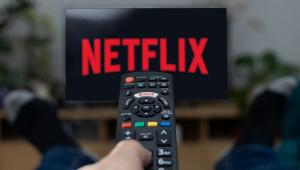 usuário aciona o controle remoto de televisão para ligar a Netflix