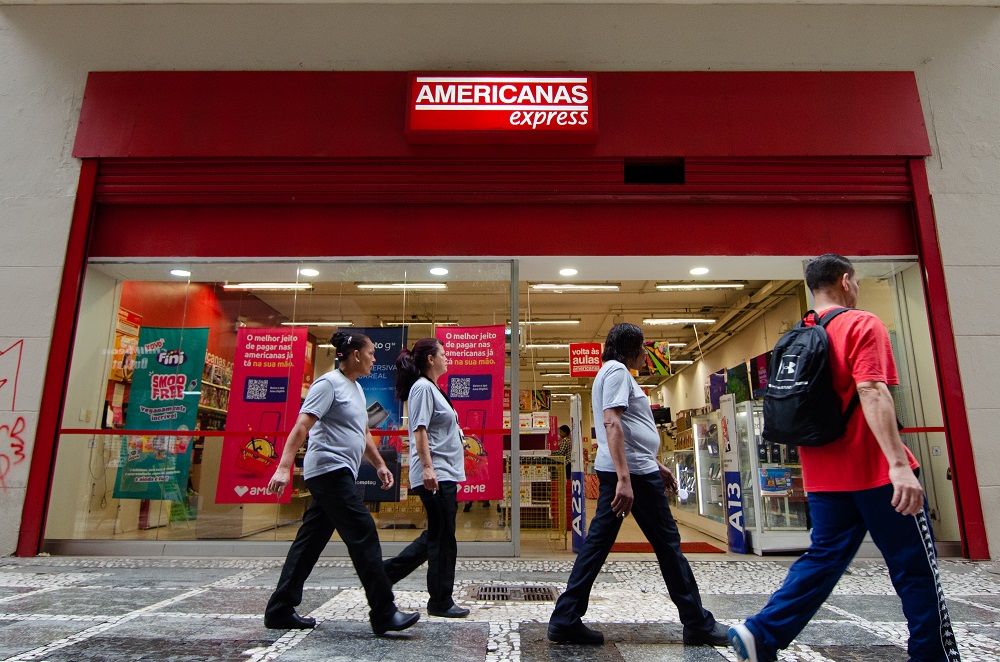 Transeuntes passam em calçada em frente a Lojas Americanas