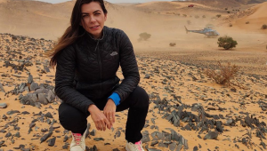 Letícia Datena agachada no deserto onde é disputado o rali Dakar