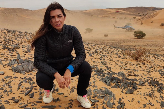 Letícia Datena agachada no deserto onde é disputado o rali Dakar