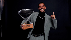 Filipe Toledo, com traje esporte fino, segura taça do prêmio WSL Awards