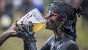 Folião bebe cerveja durante o "Bloco da Lama", uma festa de carnaval de lama, em Paraty