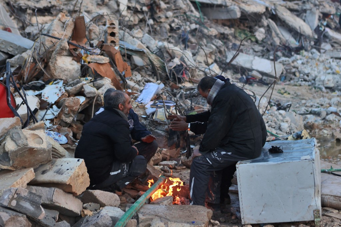 Equipes de resgate sírias tentam se aquecer em meio à destruição provocada pelo terremoto