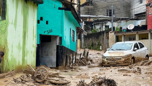 Rua em São Sebstião coberta de água barrenta, com carro e bicicleta destruídos