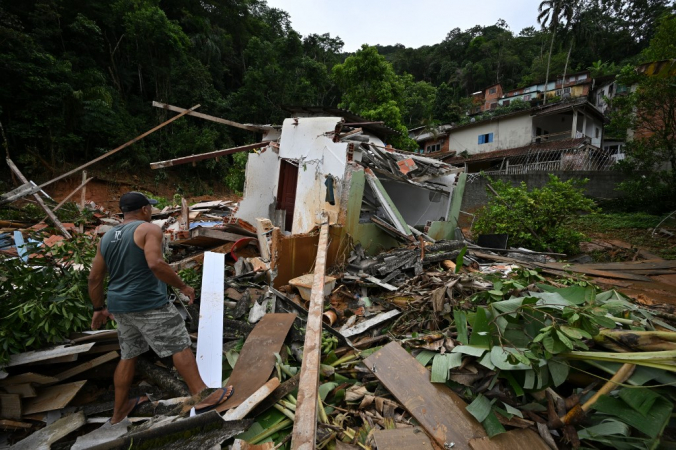 Homem caminha entre os escombros em uma área afetada por enchentes no distrito de Juquehy, em São Sebastião, região mais afetada pelas chuvas