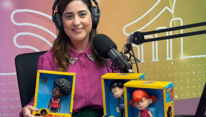 Jovem mulher branca segura caixas de brinquedos com personagens infantis em um estúdio