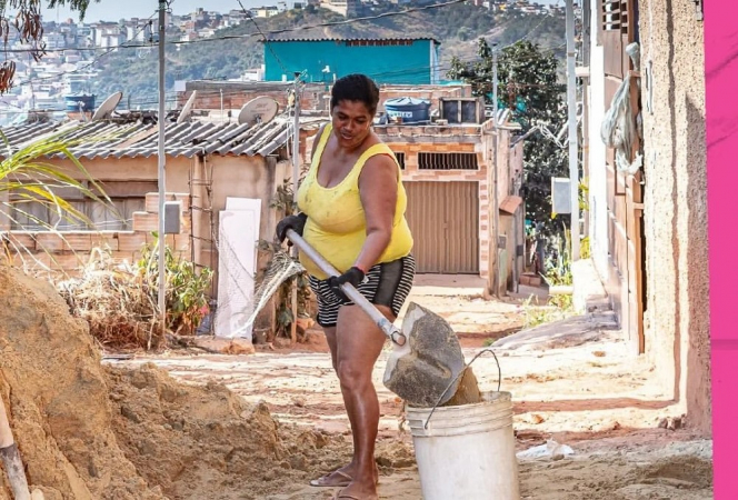 Mulher com pá jogando terra no balde em casa na favela