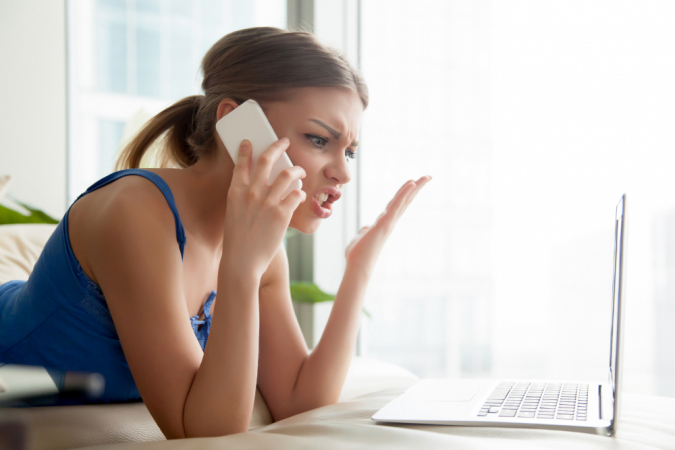 Jovem mulher branca fala ao telefone reclamando de algo