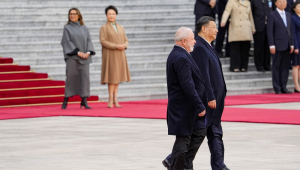 Lula caminha ao lado de i Jinping, e ao fundo aparecem Janja e a primeira-dama chinesa