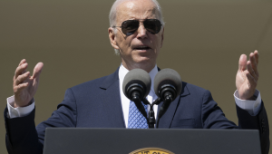Joe Biden de óculos escuros em frente a um púlpito