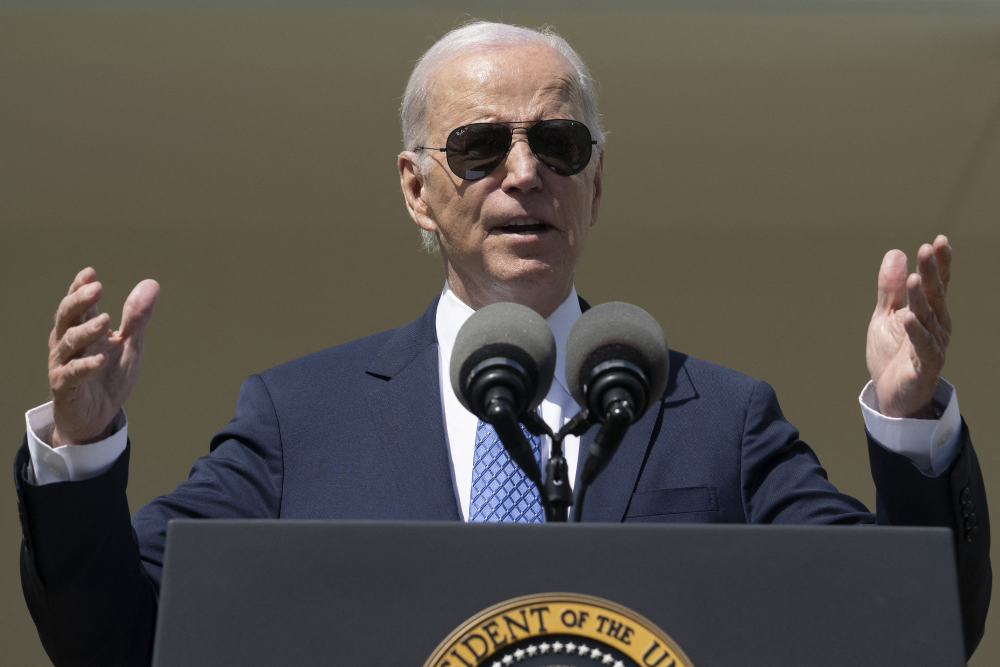 Joe Biden de óculos escuros em frente a um púlpito