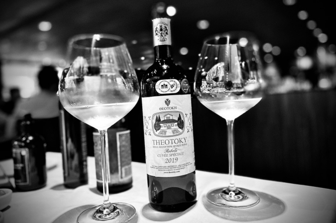 Foto em preto e branco de garrafa de vinho na mesa com duas taças