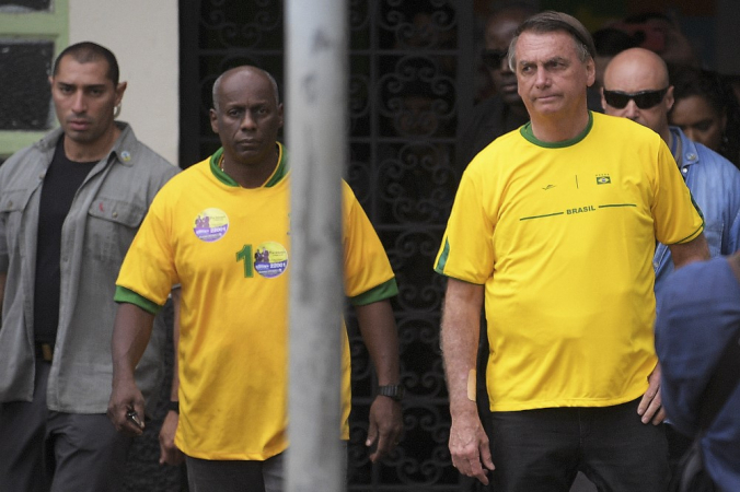 O presidente brasileiro e candidato à reeleição Jair Bolsonaro (C) parte, acompanhado por Ailton Gonçalves Moraes Barros, major reformado do Exército, após votar nas eleições legislativas e presidenciais no Rio de Janeiro