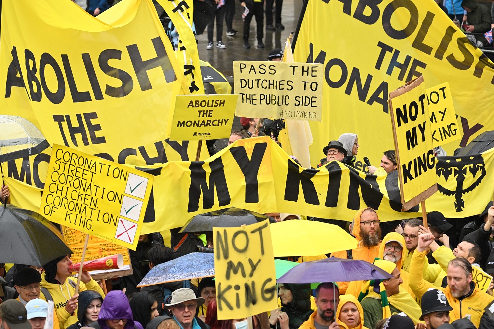 Manifestantes acenam com placas "Não é meu rei" perto da 'Procissão do Rei'