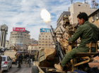 Um combatente rebelde sírio dispara tiros enquanto pessoas comemoram perto da Torre do Relógio, na cidade central de Homs