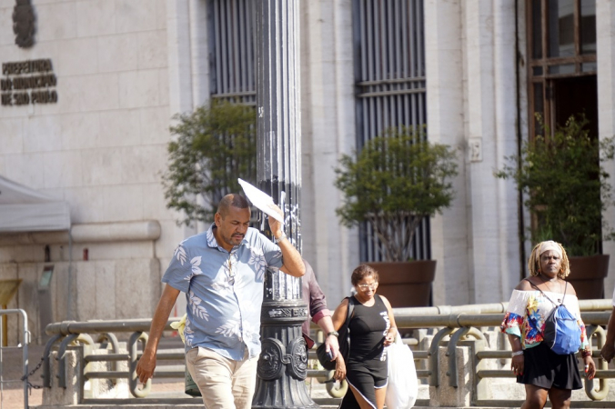 Pedestre se protege do sol no Viaduto do Chá, na região central de São Paulo