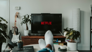 Homem com os pés na mesa assiste à TV logada no Netflix
