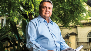 O x-ministro Roberto Rodrigues sentado no jardim com um livro na mão