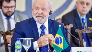 Lula sentado em lugar cmo água e uma bandeirinha do Brasil durante Abertura da Reunião de Presidentes dos países da América do Sul