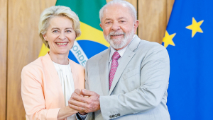 Ursula Von der Leyn e Lula posam com as mãos entrelaçadas; atrás, as bandeiras do Brasil e da União Europeia