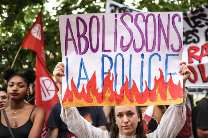 Manifestante segura um cartaz com os dizeres 