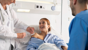 Mulher sorridente na cama de hospital recebe injeção