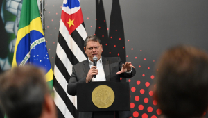 Tarcísio de Freitas discursa em púlpito e gesticula em frente às bandeiras de São Paulo e Santos
