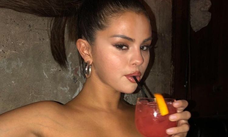 Selena Gomez com bebida vermelha na mão