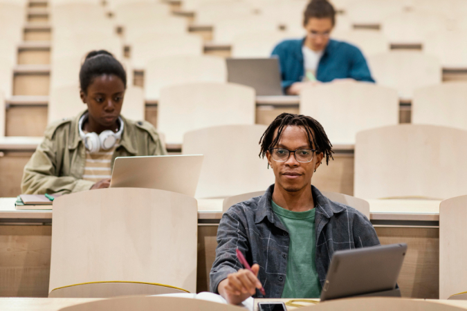 Três alunos em uma faculdade tipicamente americana, em sala no estilo anfiteatro