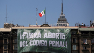 Um banner com os dizeres: "Aborto Fora do Código Penal" pendurado em um prédio durante o Dia Internacional da Mulher, na Praça Zócalo, na Cidade do México
