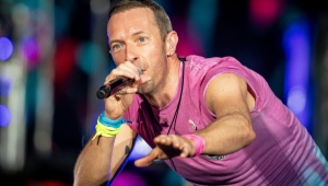 Chris Martin, do Coldplay, canta com camisa rosa em show