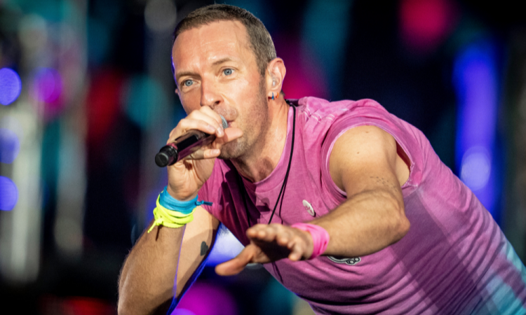 Chris Martin, do Coldplay, canta com camisa rosa em show