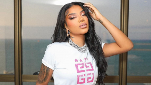 Ludmilla de camiseta branca e com a mão esquerda na cabeça