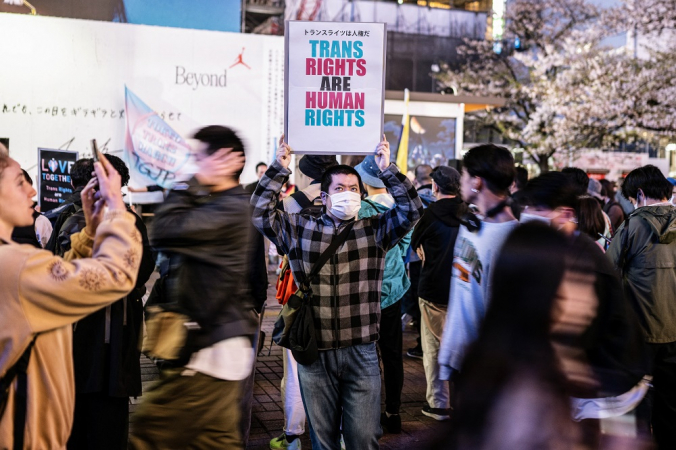 Um participante segura um cartaz durante o comício do Dia Internacional da Visibilidade dos Transgêneros no distrito de Shibuya, em Tóquio
