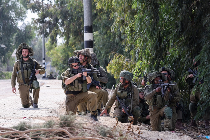 Soldados israelenses assumem posição em Kfar Aza, no sul de Israel, na fronteira com a Faixa de Gaza