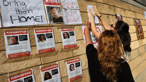 Apoiadores e familiares de reféns israelenses sequestrados pelo grupo militante palestino Hamas na semana passada em um ataque surpresa a Israel, colam suas imagens em uma parede durante um comício fora da base militar israelense de HaKirya, no centro de Tel Aviv