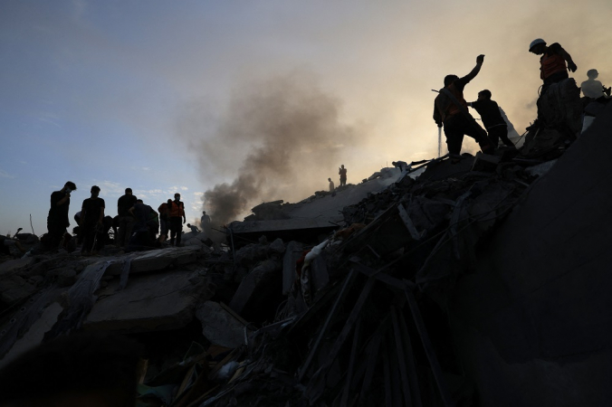 Palestinos procuram sobreviventes nos escombros de um prédio no campo de refugiados de Nuseirat, no centro da Faixa de Gaza