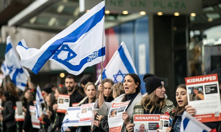 Pessoas agitam bandeiras israelenses e seguram cartazes com reféns do Hamas durante um protesto em frente à sede da ONU
