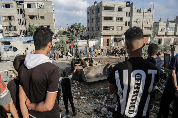 Palestinos procuram corpos e sobreviventes nos escombros de um edifício residencial destruído por um ataque aéreo israelense