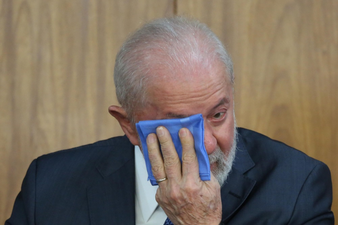 Lula passa um pano azul no rosto