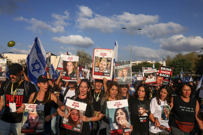 Parentes, amigos e apoiadores de reféns israelenses detidos em Gaza desde o ataque de 7 de outubro por militantes do Hamas no sul de Israel, seguram cartazes e imagens daqueles tirados durante um protesto pela sua libertação