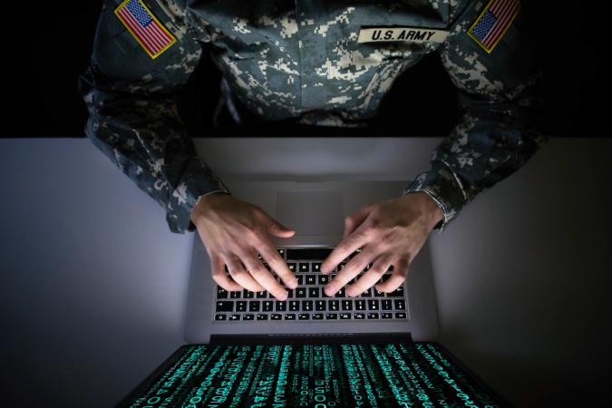 Vista por cima de militar amnericano mexendo em computador com série de dados na tela