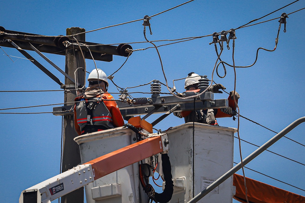 Funcionários da concessionária ENEL fazem manutenção em cabos para o restabelecimento da energia elétrica na região do Parque Novo Mundo