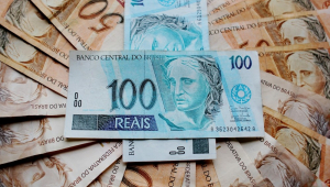 Notas organizadas e sobrepostras, com duas de R$ 100 cruzadas no topo